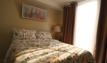 a bed with a floral comforter and lamp